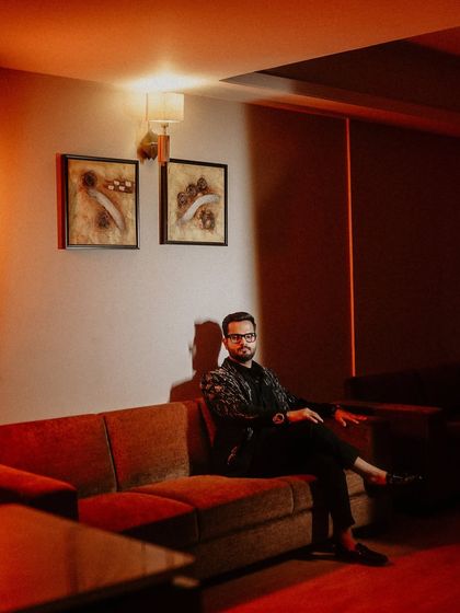 A relaxed and cool portrait of the groom. The warm, dramatic lighting and his comfortable pose on the sofa create a stylish and cinematic image.