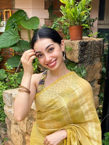 A happy, festive look in a beautiful yellow saree. This candid-style photo is great for social media content, capturing the genuine joy and spirit of the festive season.