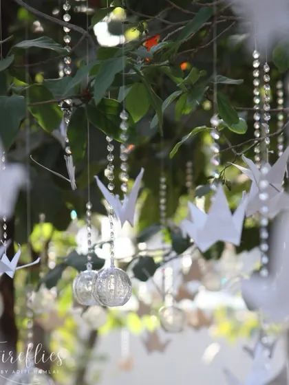 A beautiful detail of the decor, with handcrafted origami paper cranes and crystal strings hanging from the trees, adding a touch of delicate artistry and magic to the ambiance.