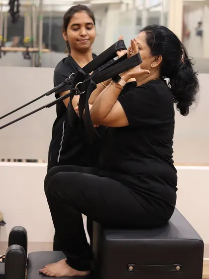 Here, a trainer works closely with a client on a seated Reformer exercise. This level of focus is crucial for clients recovering from injury, as it ensures movements are controlled and therapeutic.