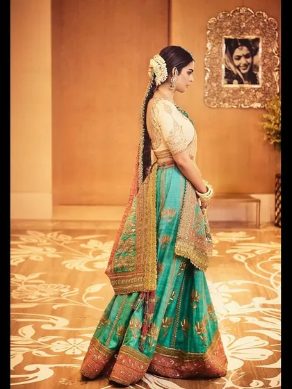 A side profile of Isha Ambani Piramal in a multi-hued Anuradha Vakil lehenga. The look is completed with a traditional gajra braid, showcasing a classic approach to Indian bridal and festive styling.