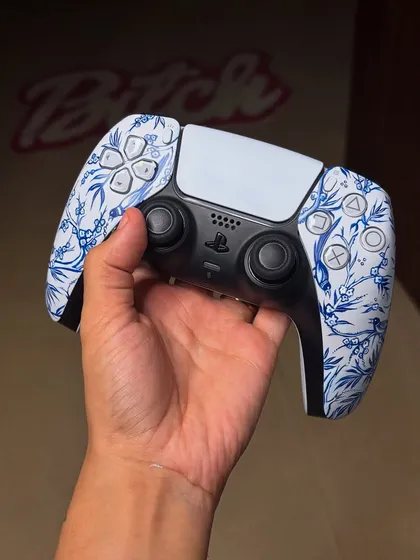 The finished "Qinghua" inspired PS5 controller, held up to show the intricate, hand-painted blue floral design.