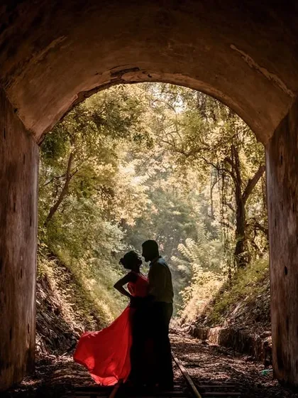 This is an example of my more artistic, storytelling photography. A couple is silhouetted against the light at the end of a tunnel, with the bride's red dress providing a vibrant pop of color. I use light and shadow to create dramatic and memorable pre-wedding photos.