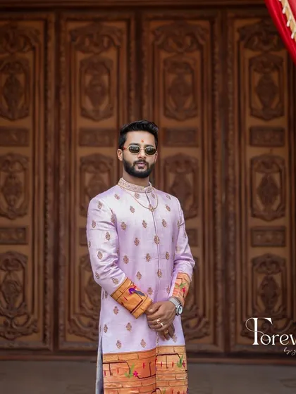 This is a closer look at a bespoke sherwani I crafted from Paitani silk. The soft lavender color is complemented by traditional motifs along the hem and cuffs, making it a standout piece for a groom who values classic elegance.
