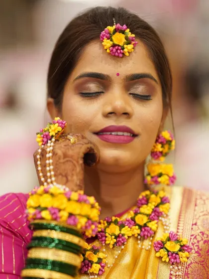 A serene moment for the Haldi bride. The soft brown smokey eye and matte pink lip complement her yellow and pink saree beautifully.