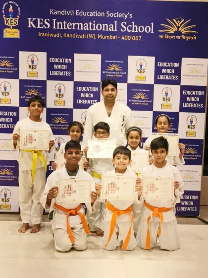 Another proud group from our KES International School program, displaying their new belts and certificates with their instructor.