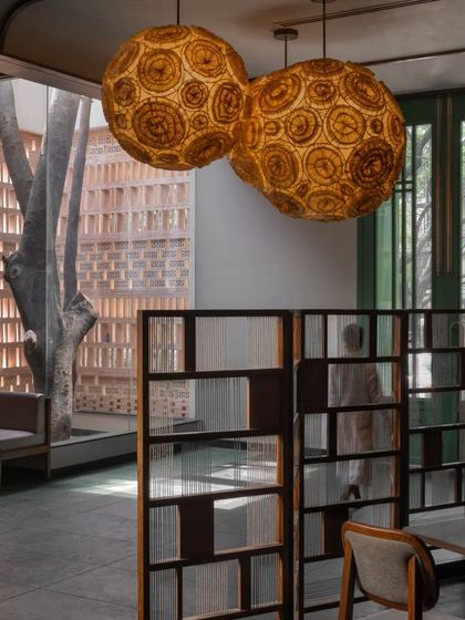 A close-up of the large, spherical pendant lights made from natural fibers. These custom lighting fixtures are a centerpiece of the design, casting a warm, diffused glow that enhances the restaurant's earthy material palette.