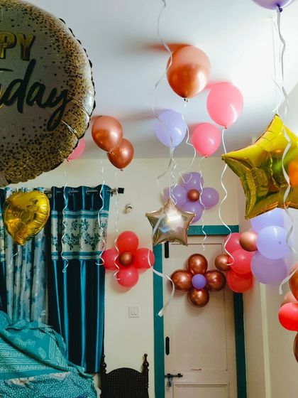 A simple room decoration for a birthday, with colorful balloons floating on the ceiling and arranged on the walls.
