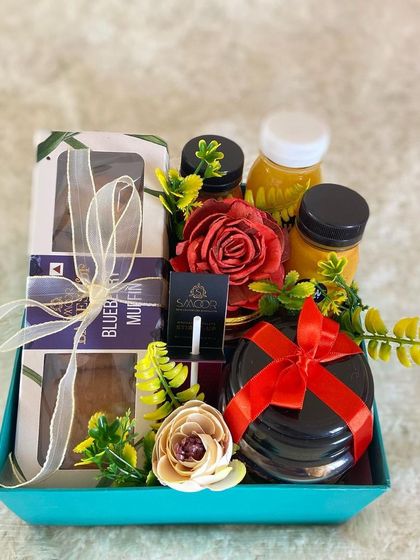 A sweet and simple care package ready for delivery. This hamper includes blueberry muffins, healthy juices, and a car fragrance diffuser, designed to bring a little brightness to someone's day.
