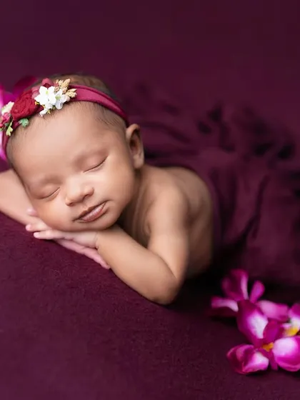 The classic 'chin on hands' pose, showcased here with a simple, elegant plum wrap. This pose is a favorite for showing off a baby's peaceful face.