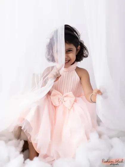 A peek-a-boo smile from behind a sheer curtain. This dreamy setup with soft, white fabrics creates such a sweet and angelic portrait.