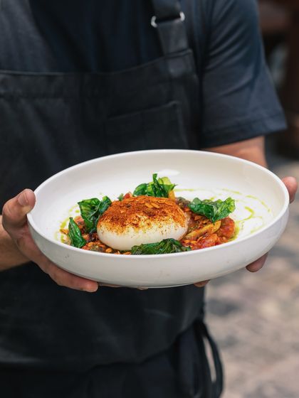 Say cheese. I'm presenting our beautiful Burrata Salad, a perfect sphere of fresh cheese nestled in a bed of tomatoes and pesto.