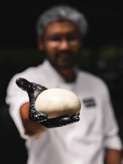 A chef proudly holds up a freshly made ball of mozzarella. This is the quality you can taste on our pizzas and salads.