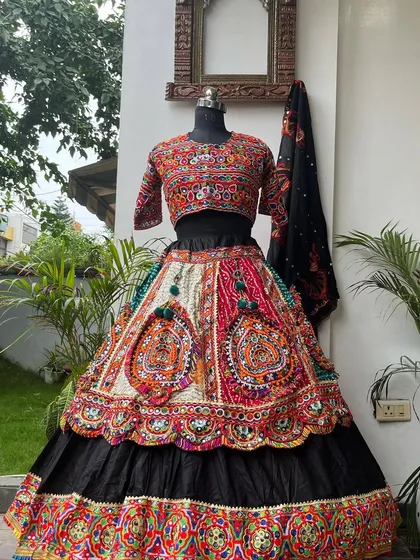 The full view of this beautiful black and red lehenga. The skirt features large, colorful embroidered patches that make a bold statement.