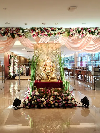 For a traditional and auspicious beginning, we designed this beautiful entrance around a Ganesha idol. The setup includes soft pink drapes, a canopy of flowers, and lush greenery, creating a serene and welcoming focal point.