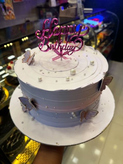 A lovely birthday cake with a soft lavender and pink ombre effect. The delicate butterflies and pearl sprinkles add a touch of whimsy and elegance to the design.