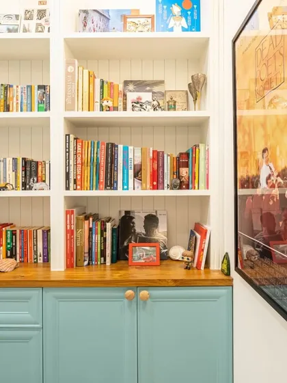 A serene study room created by renovating a washroom, featuring aqua blue cabinets, a raw wood log tabletop, and ample bookshelves.