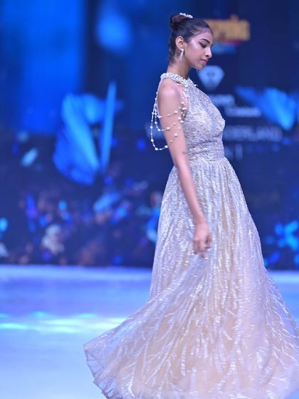 A side view of this shimmering golden gown, detailed with a delicate pearl shoulder strap for an extra touch of luxury.