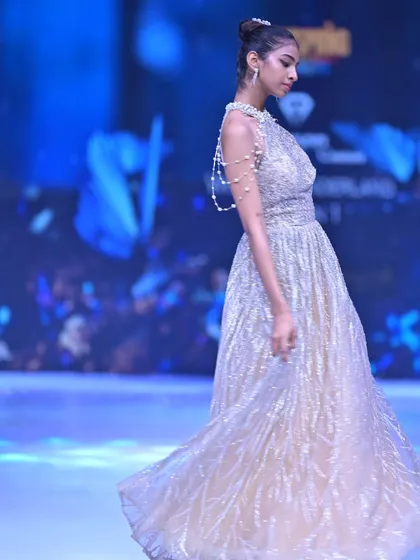 A side view of this shimmering golden gown, detailed with a delicate pearl shoulder strap for an extra touch of luxury.