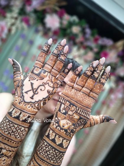 A close-up of the palms from the full bridal set, highlighting the custom initial and the detailed filler work surrounding it.