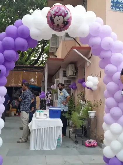 A classic Minnie Mouse balloon arch in purple and white, creating a grand and cheerful entrance for a birthday celebration. The large character foil balloons add a perfect thematic touch.