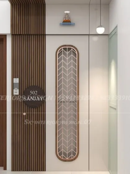 A clean and modern entrance design. The main door features a vertical jali panel, and the adjacent wall has wood fluting and a simple nameplate.