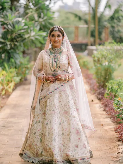 A full-length shot of the bride in her beautiful beige and pastel lehenga. The look is modern yet traditional, perfect for a daytime wedding.