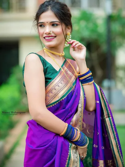 This vibrant purple Paithani saree with a green border is a perfect example of a festive Maharashtrian look. The drape is kept clean and elegant to let the colors and the fabric shine.