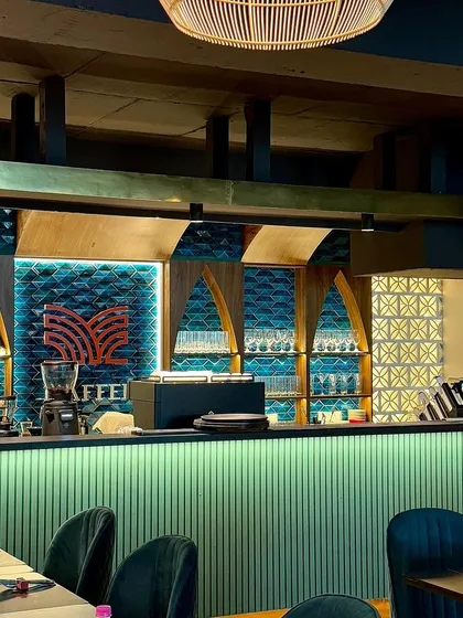 The warm glow of our bar at night. The arched shelving and geometric patterns are inspired by Mediterranean architecture, creating a cozy and stylish corner for guests to gather.