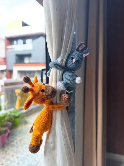 Our giraffe and bunny curtain ties in action! This photo shows how they wrap their arms around the curtain, adding a playful and unique touch to a room.