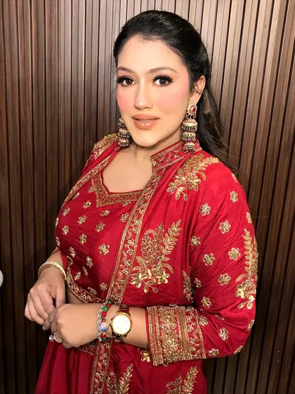 A full shot of the client in her red sharara, the heavy gold jhumkas making a traditional statement.