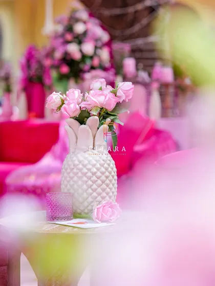 A soft-focus shot highlighting a quirky pineapple-shaped vase with delicate pink roses. It's these small, playful details that add personality and charm to our tablescapes.