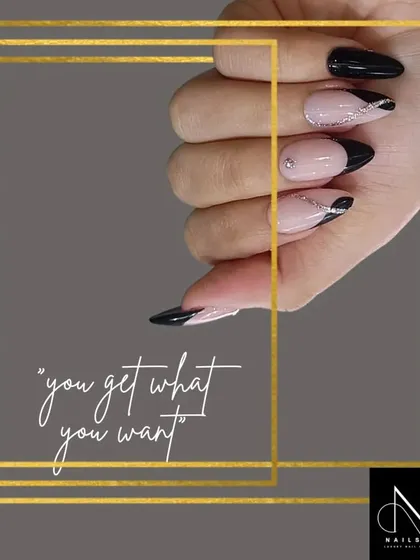 A sophisticated and edgy French manicure. This design uses a sharp, pointed black tip on an almond-shaped nail, with delicate silver glitter lines for added dimension.