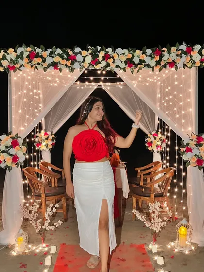 Posing at a beautifully decorated beachside dinner setup in Goa. My red floral top and white slit skirt made for a romantic and stylish dinner outfit.