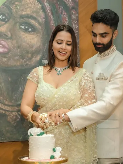 A joyous cake-cutting moment during an indoor engagement celebration in Pune. The couple's happiness is the focus, framed by modern decor and a beautiful piece of art, capturing the celebratory spirit of the occasion.
