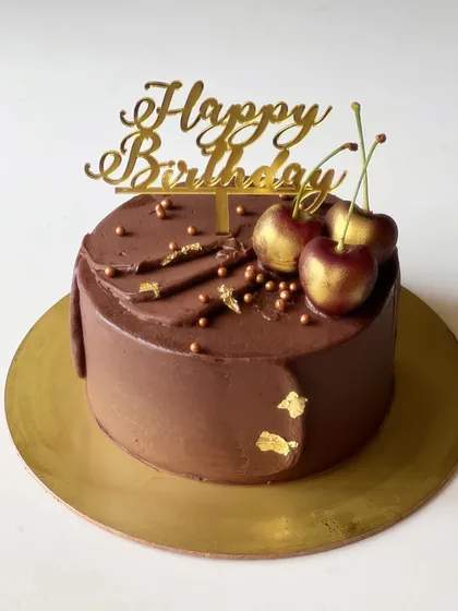 A rich and decadent Chocolate Cherry cake. This design features a smooth chocolate buttercream finish, topped with gold-dusted fresh cherries for an elegant look.