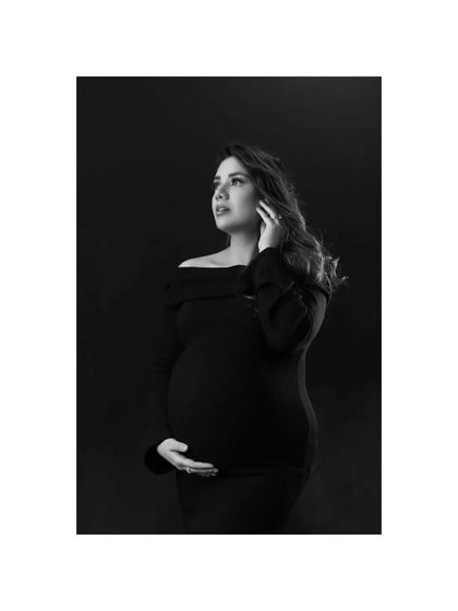 A dramatic and artistic black and white portrait. The mother-to-be looks up towards the light, her expression full of hope, creating a powerful and emotive image.