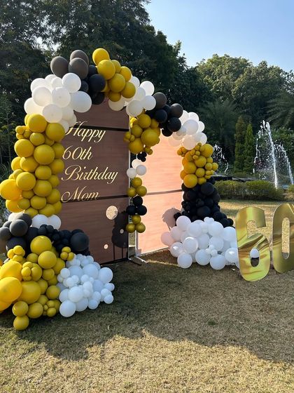 A wide shot of the 60th birthday decor in a beautiful garden setting with a fountain in the background.