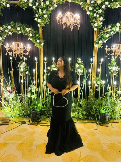 A plus-size client looking stunning in a black handwork fish-cut gown for a cocktail night. The heart-shaped bag adds a fun touch.