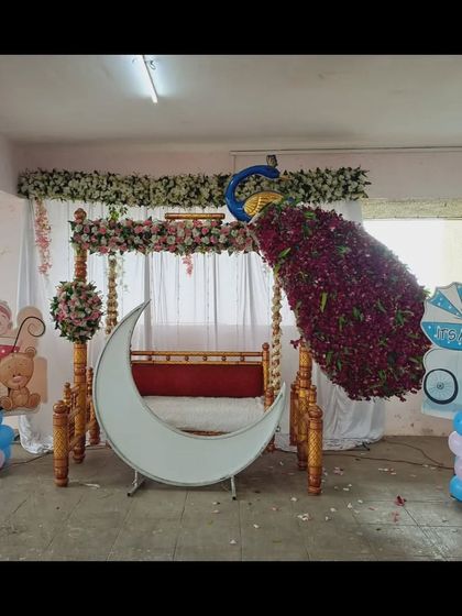 A beautiful baby shower setup in what appears to be a parking garage or open space, showing my team's ability to decorate any location. The decor features a peacock, swing, and moon prop.