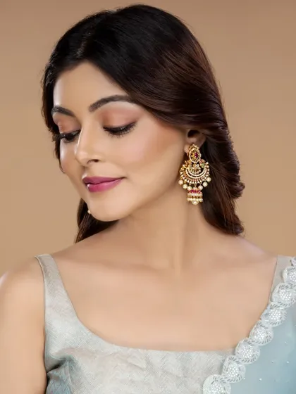 This close-up shot focuses on a pair of ornate traditional-style earrings with a modern twist. The model's downward gaze directs all attention to the jewellery, making it a great e-commerce shot.