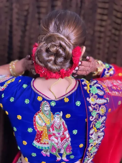 A back view of the intricate sleek twisted bun, highlighting the craftsmanship and the traditional embroidery on the bride's blouse.