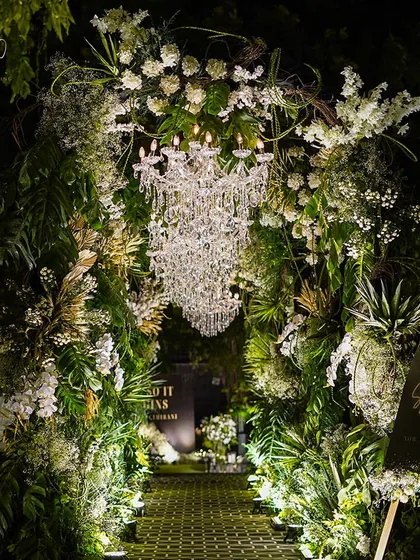 An enchanting forest-like entrance for an engagement party. I used a mix of wild greenery, white flowers, and a crystal chandelier to create a magical, immersive walkway.