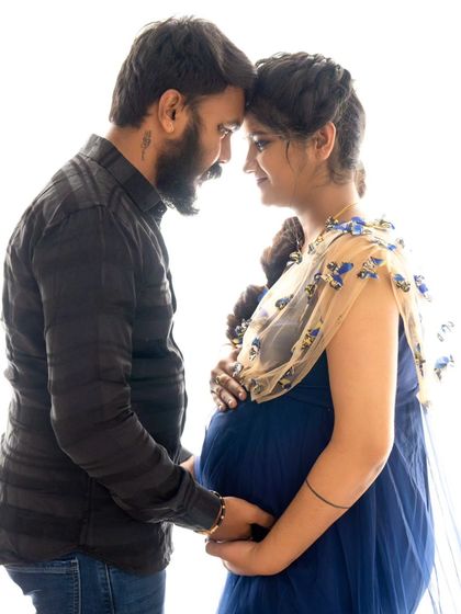 An intimate close-up of a couple touching foreheads, their hands connected over the baby bump, creating a powerful silhouette.