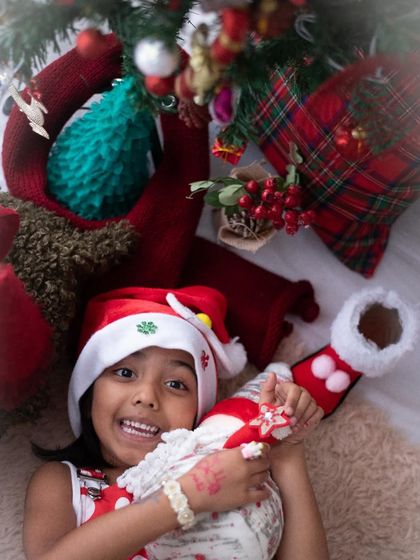 A joyful close-up from a Christmas photoshoot. The Santa hat and festive props bring out the excitement of the season in children, resulting in genuine, happy smiles.