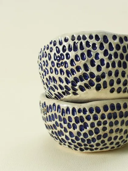 A stack of my Aqua Snack Bowls. The exterior is hand-carved to create a tactile, dotted texture that contrasts with the smooth, glossy indigo glaze on the inside.