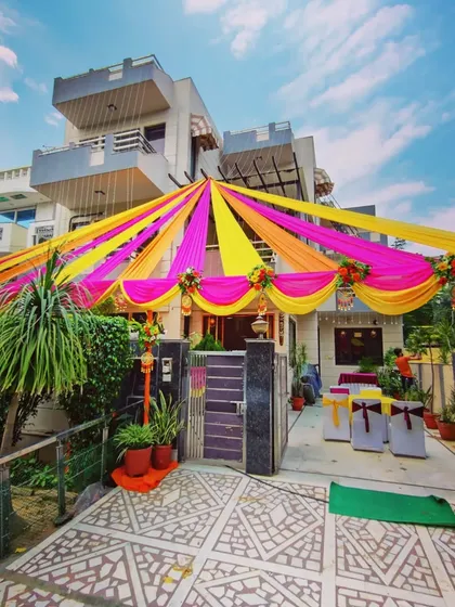 For home-based functions like a Mehandi or Sangeet, I transform the entire front of the house. Here you can see a full canopy of bright pink and yellow fabric drapes, creating a festive atmosphere right from the street.