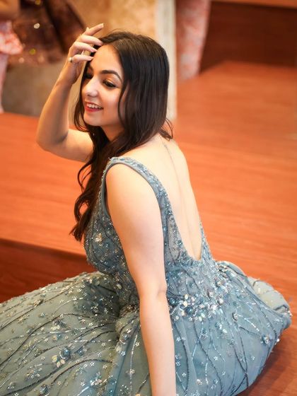 A candid, happy moment in a stunning backless ball gown. This look is perfect for a cocktail party or reception, blending Indian embellishments with a western silhouette.