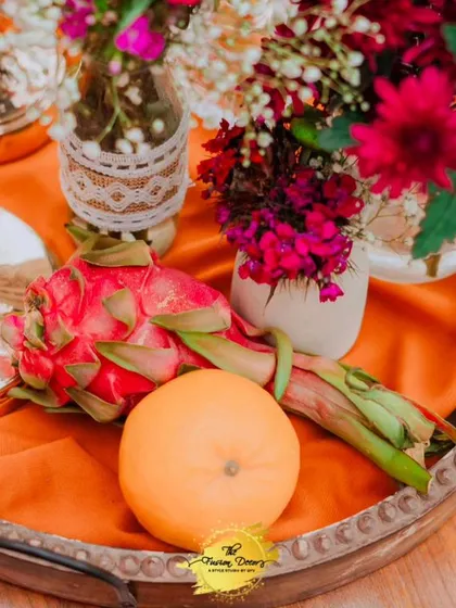 A close-up of a centerpiece detail, where fresh dragon fruit and an orange are artfully arranged with flowers, showing my commitment to unique and natural decor elements.