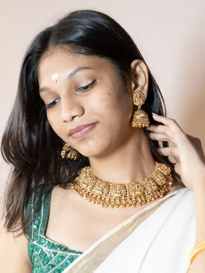 A graceful pose that highlights the entire temple necklace set. The matt gold finish looks stunning against the skin and the traditional attire.